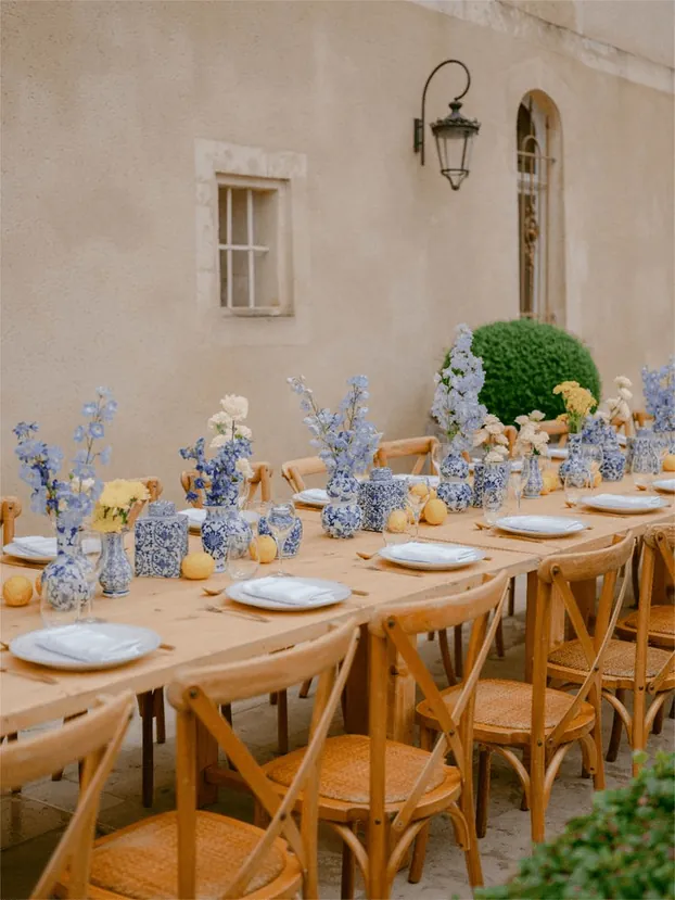 A table of blue and white flowers outside a stone house