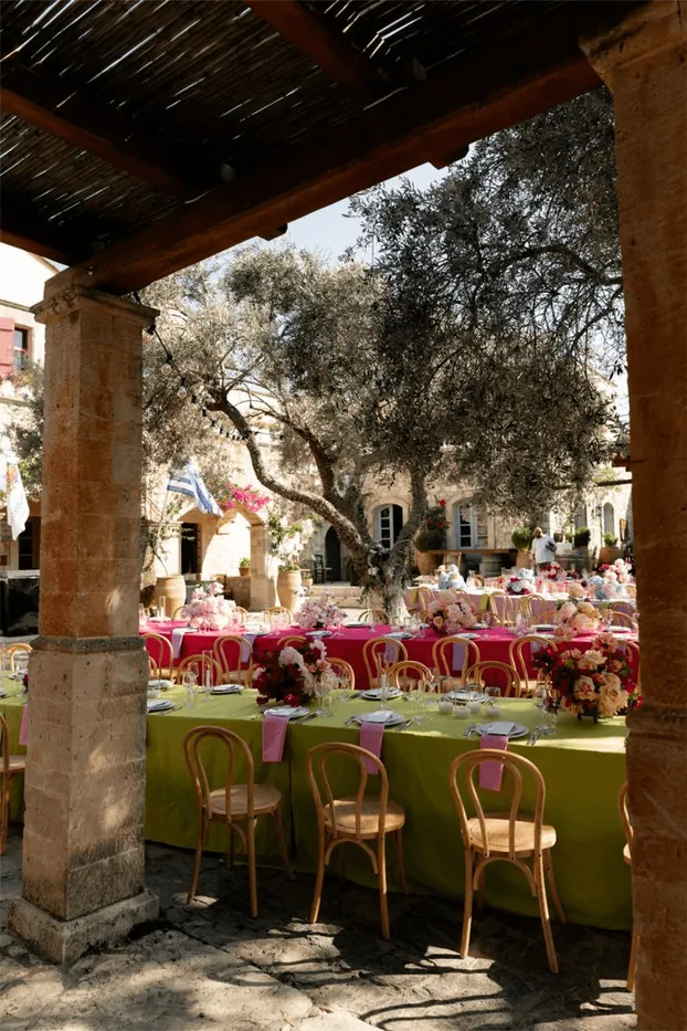 Long tables with pink flowers under a wooden pergola