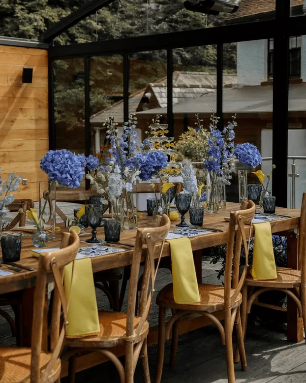 A conservatory table with blue flowers and yellow napkins