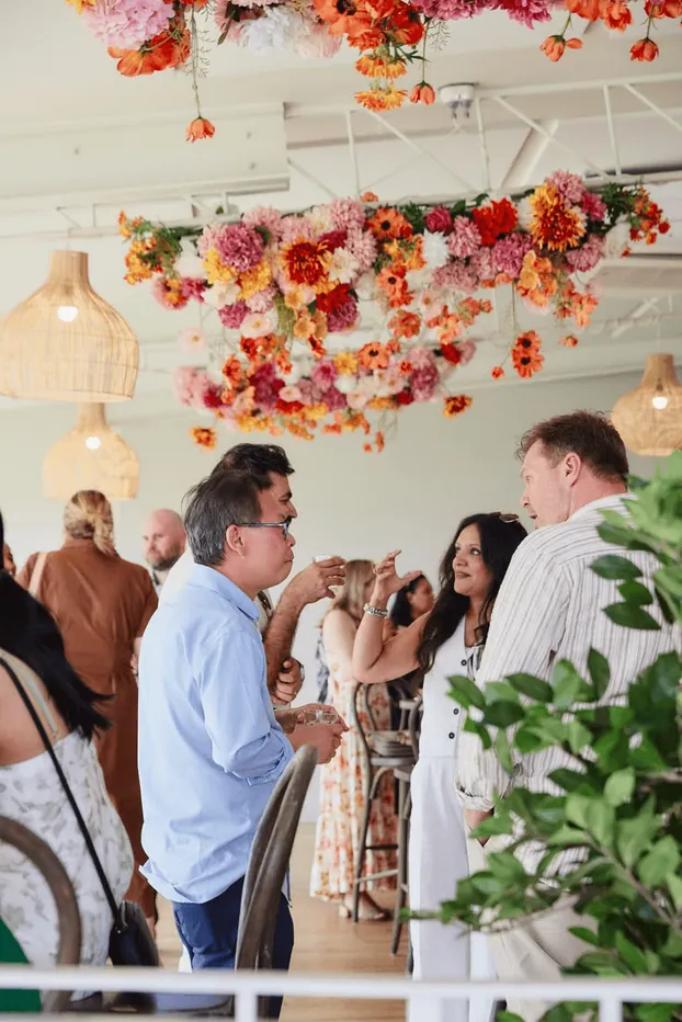Guests talking under a hanging floral installation