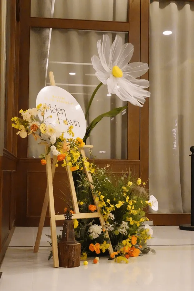 A giant paper flower and welcome sign at a doorway
