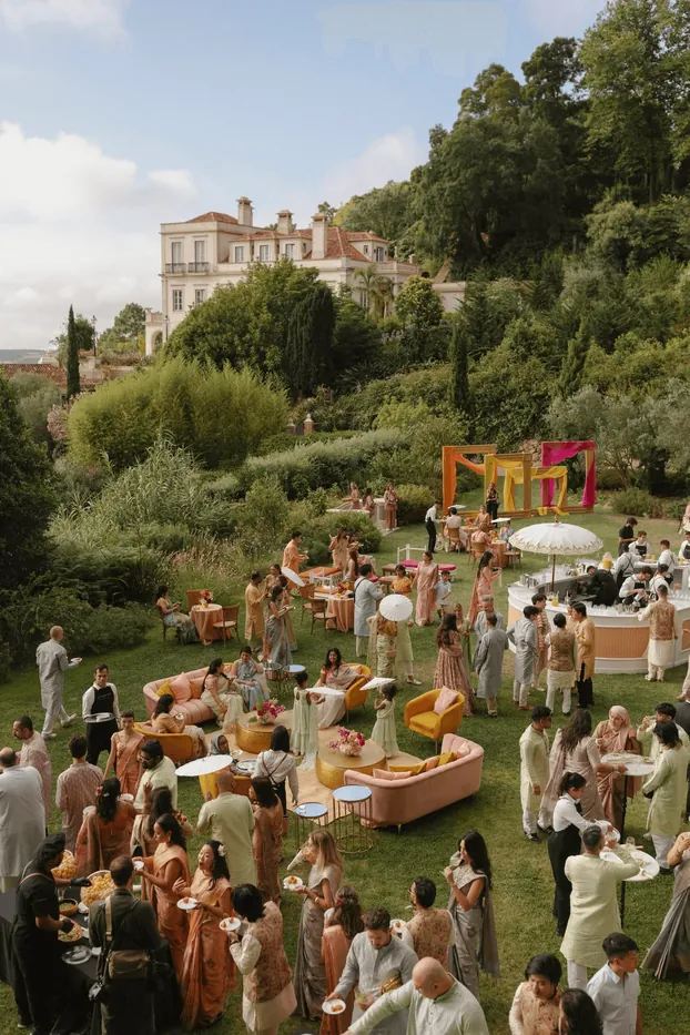 Wedding guests gathered on a garden lawn before a villa