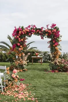 An arch of pink and red flowers on a lawn by the sea