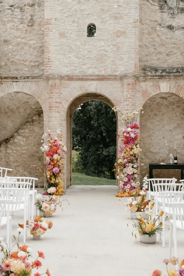 A stone archway framed with flowers and white chairs