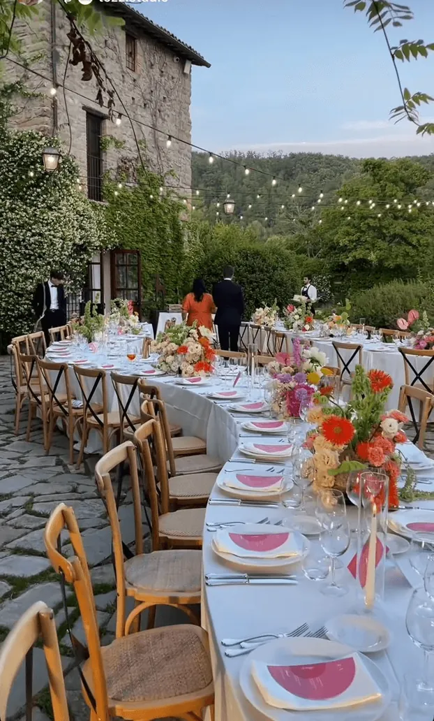 A dinner table on a stone terrace beside an old tower