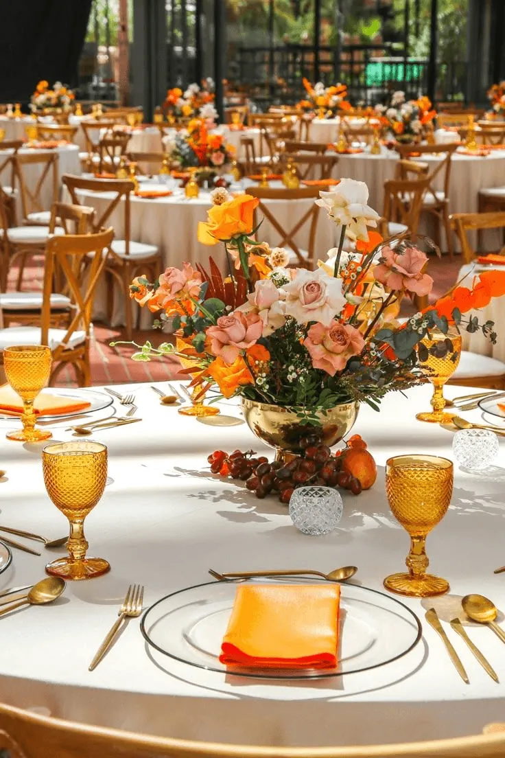 A banquet hall with amber glasses and tall floral centrepieces