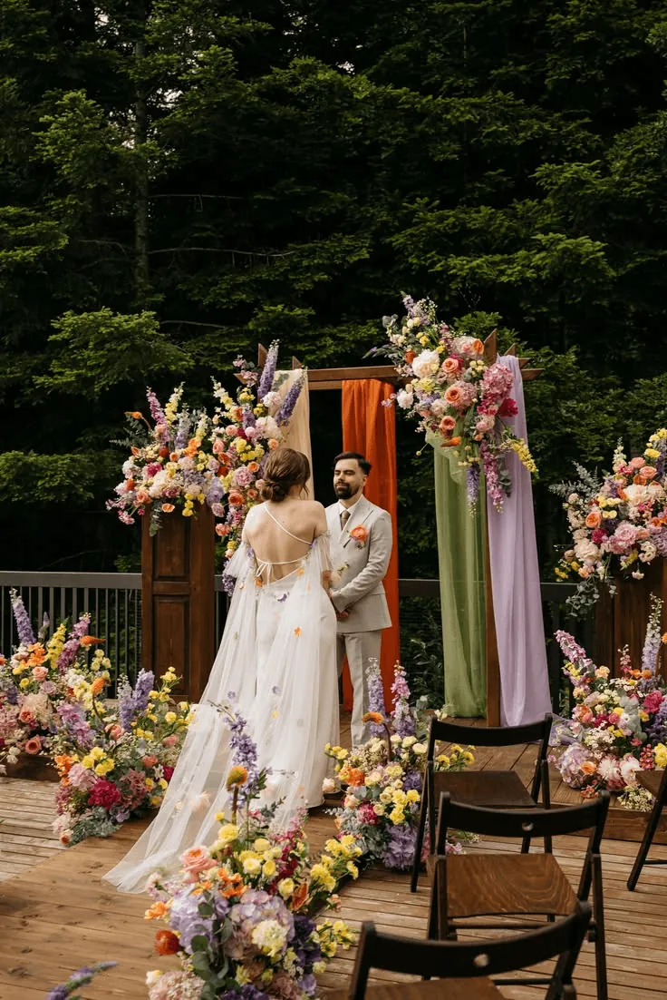 A bride and groom under a flower-covered arch in a garden