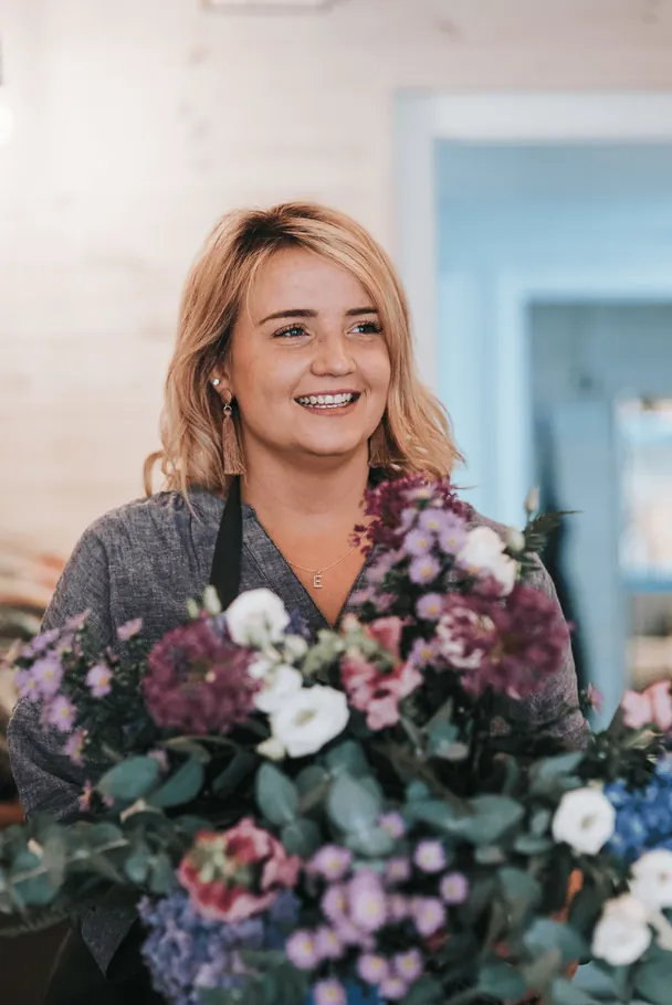 Lily Woods holding a bouquet of purple and white flowers