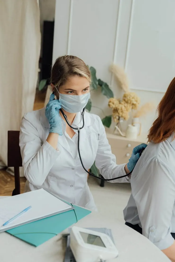 A doctor in a mask checking a patient’s blood pressure