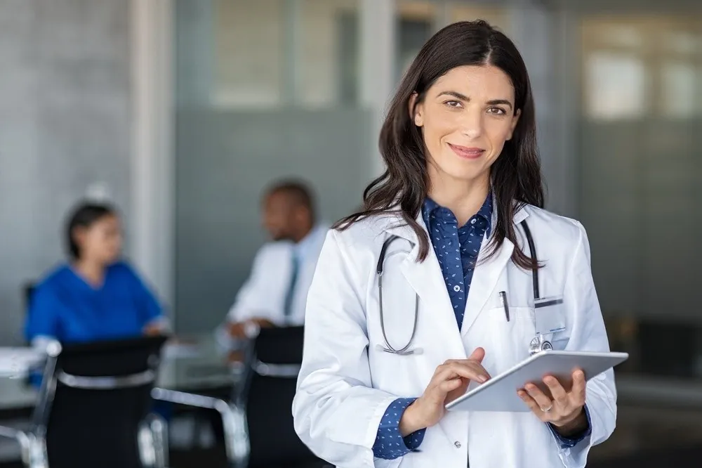 A doctor holding a tablet in a busy clinic