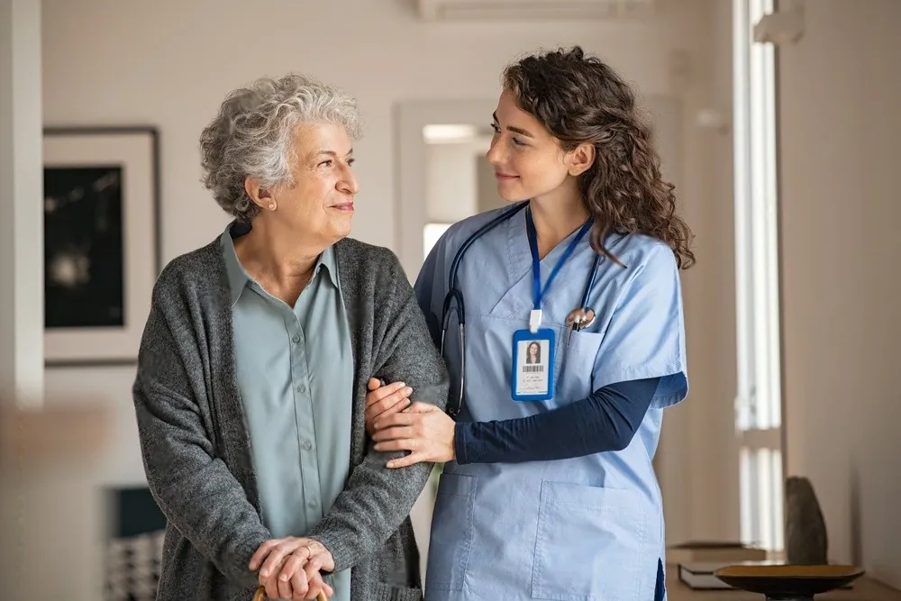 A nurse walking with an older woman