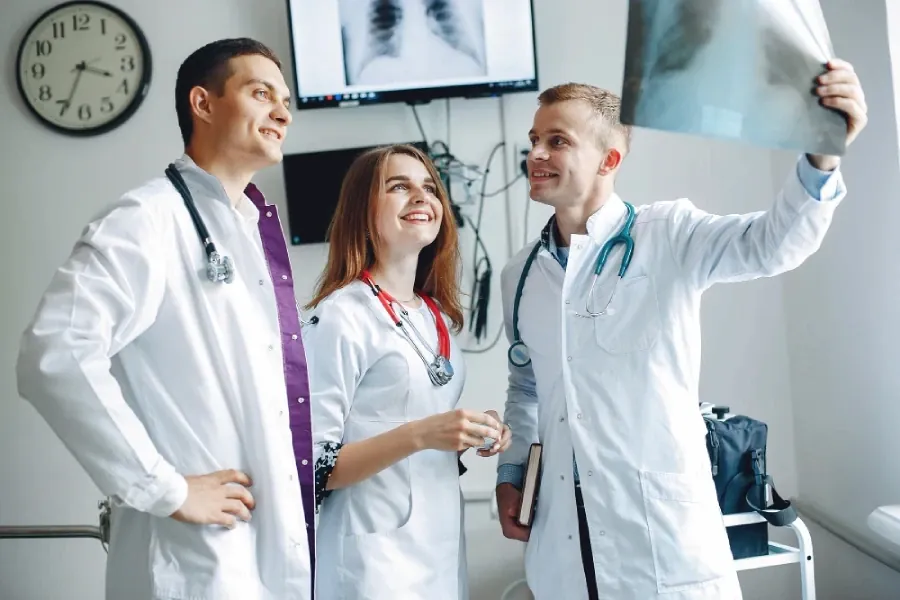 Three young doctors talking in front of x-rays