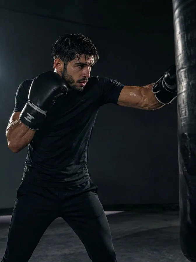 A boxer in black gloves punching a heavy bag during a boxing class