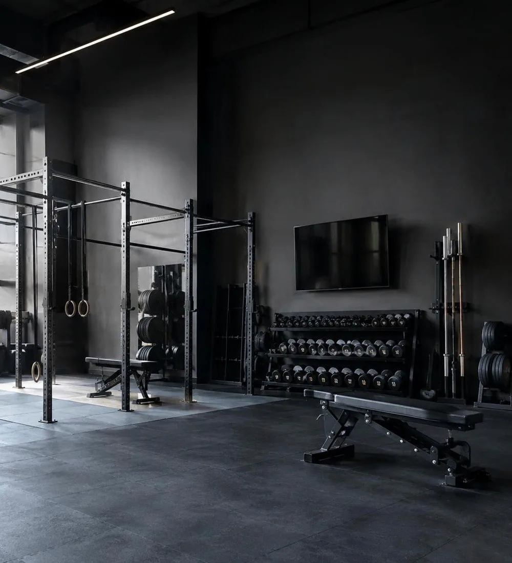 A strength area with racks, benches and dumbbells in a dark gym
