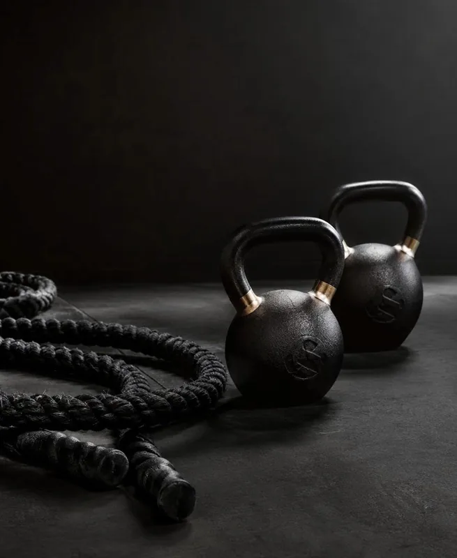 Kettlebells and a battle rope on a dark gym floor
