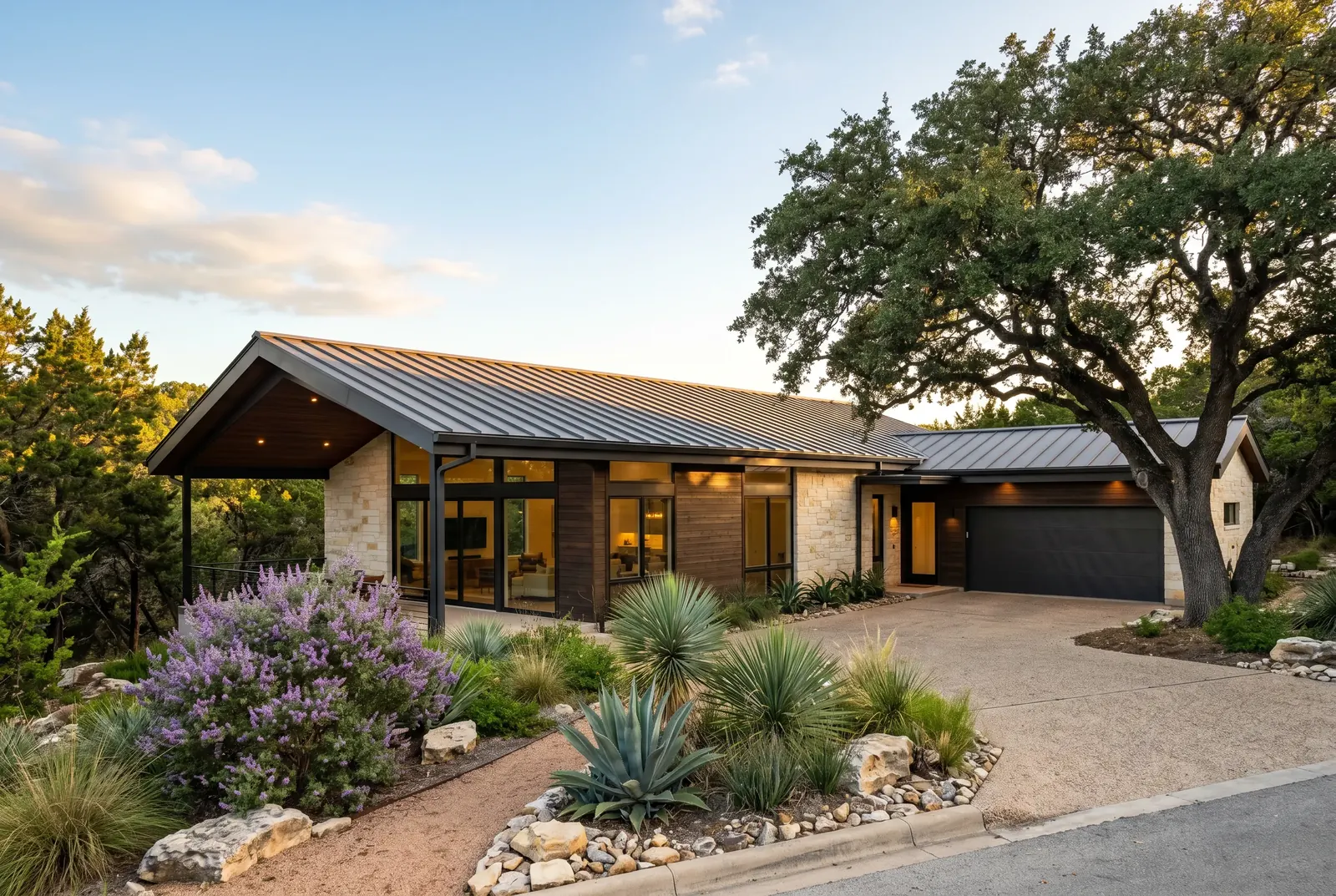 A single-story house with a landscaped garden and an oak tree at sunset