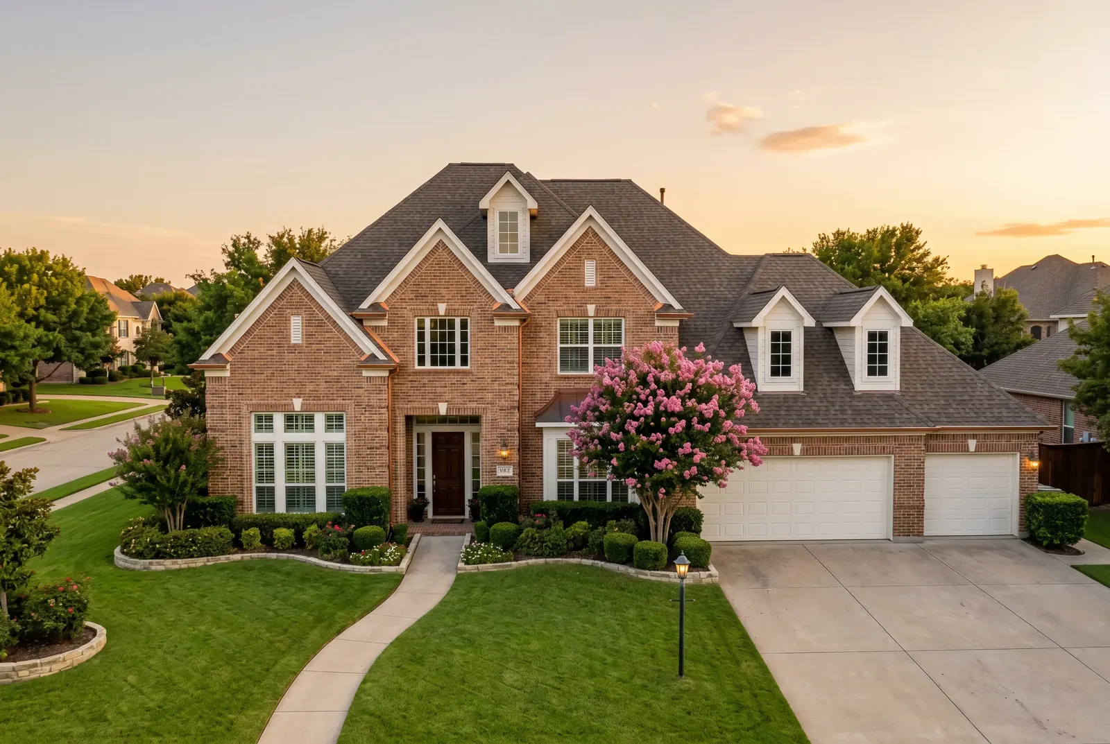A large brick house with a curved walkway and a manicured lawn