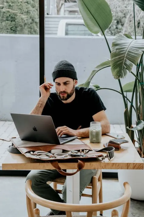 A video editor working on a laptop at a wooden table