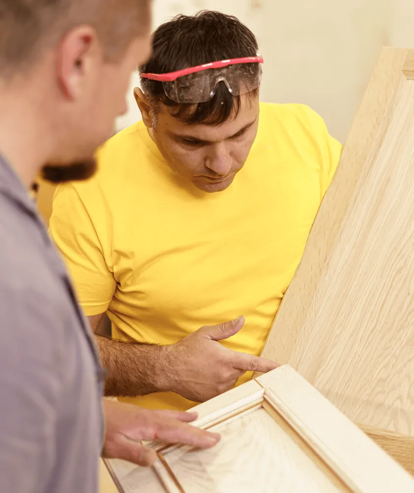 Two carpenters checking a wooden cabinet door
