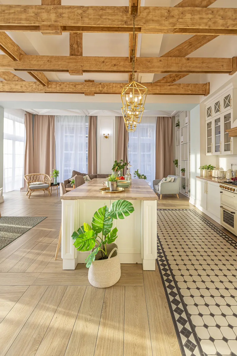 A kitchen with wooden beams and a potted plant on the island