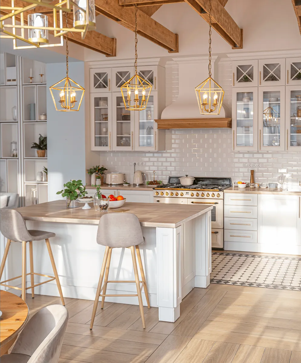 A bright kitchen with an island and gold pendant lamps