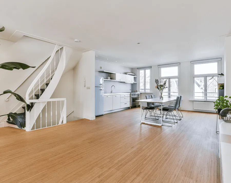 A bright open living space with wooden floors and a white staircase