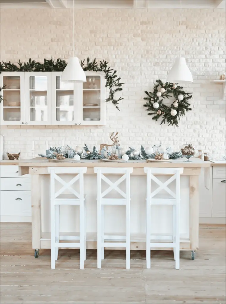 A white kitchen with a wreath and white bar stools