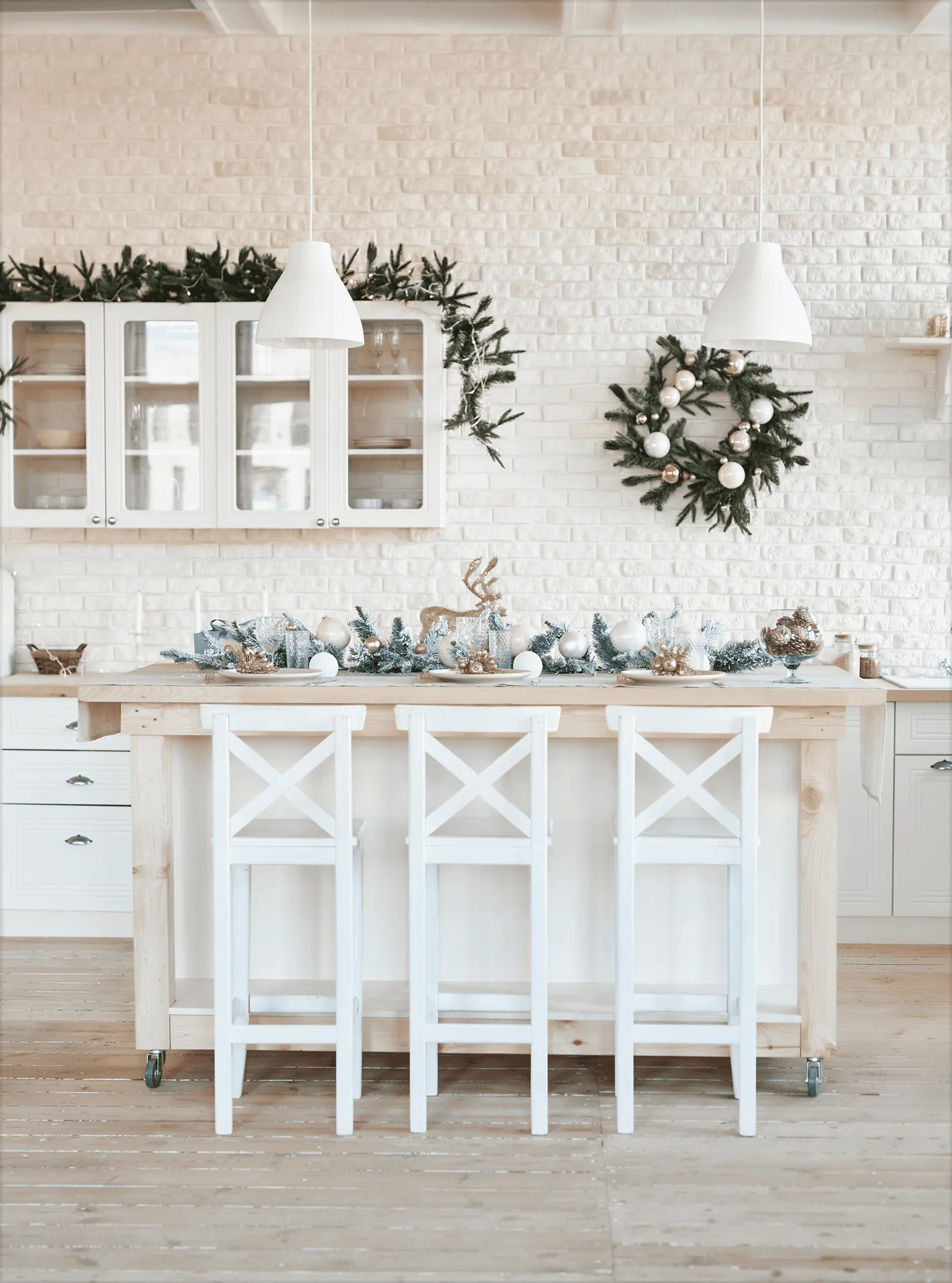 A white kitchen with a wreath and white bar stools