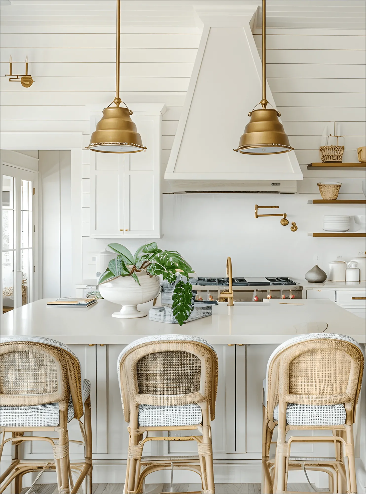 A white kitchen with brass lamps and rattan bar stools