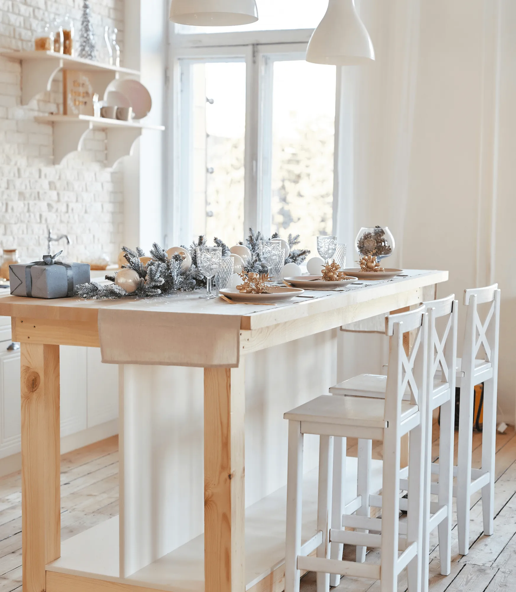 A long wooden table with white chairs by a bright window
