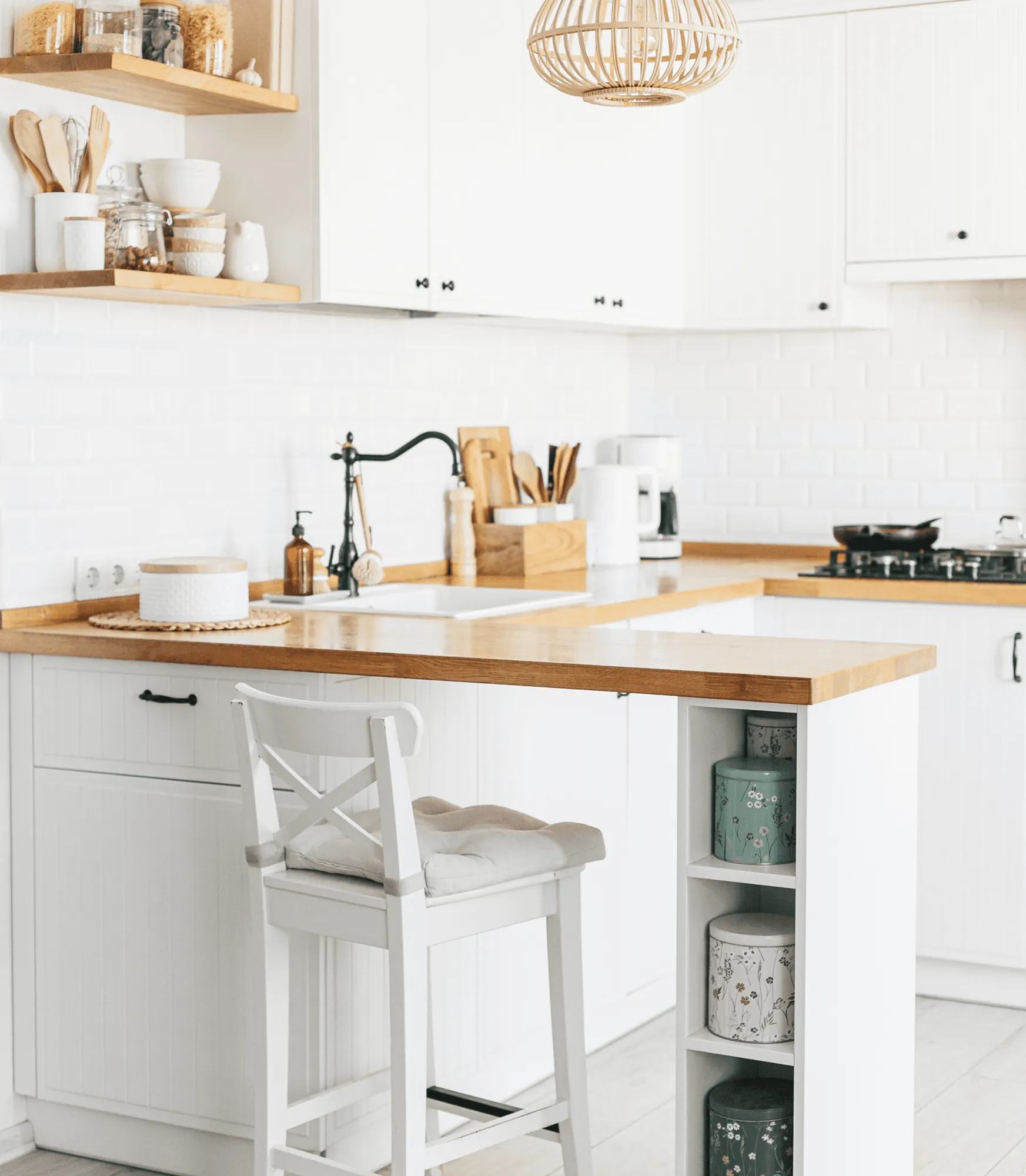 A white kitchen with a wooden worktop and a white bar stool