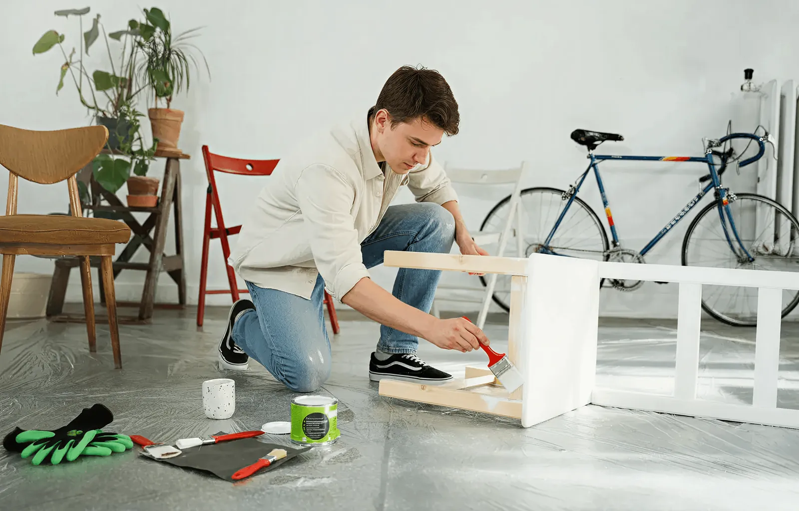 A man assembling white furniture on a concrete floor