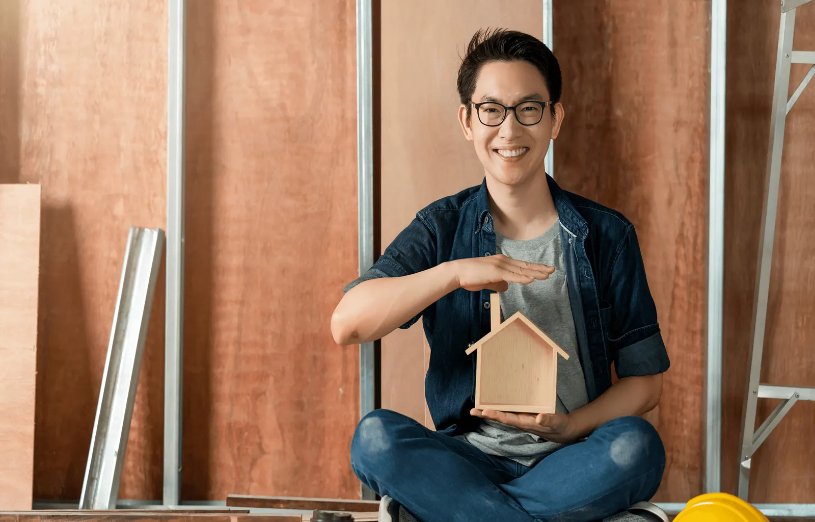 A smiling man holding a small wooden house model