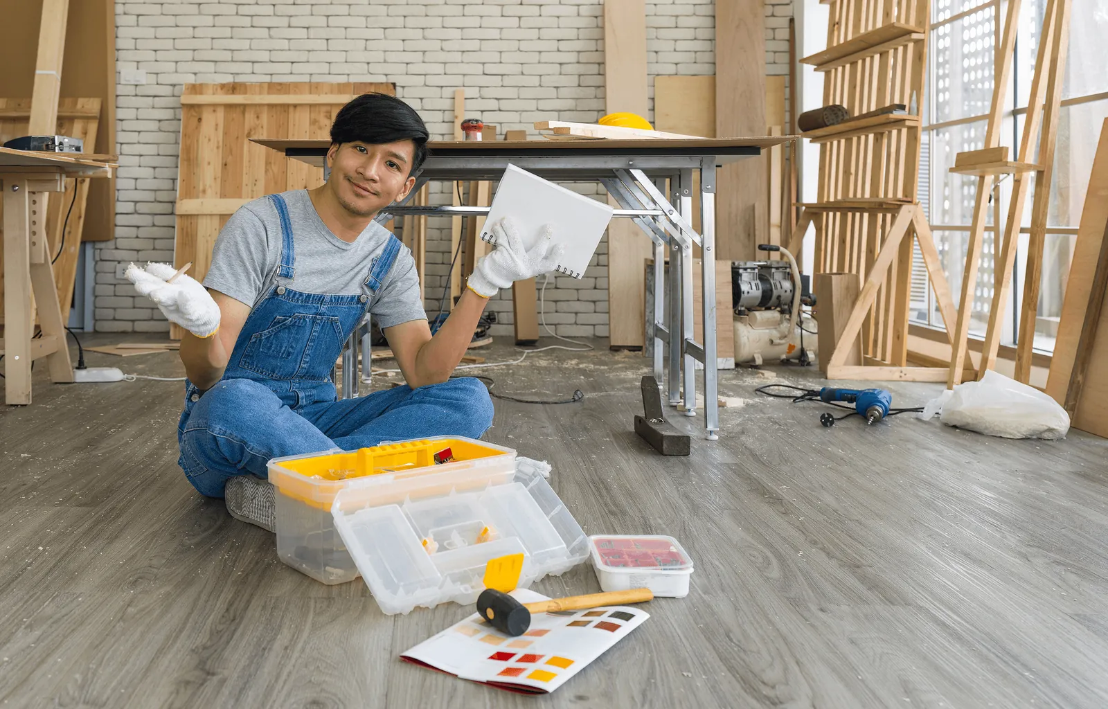 A smiling worker in overalls laying a laminate floor