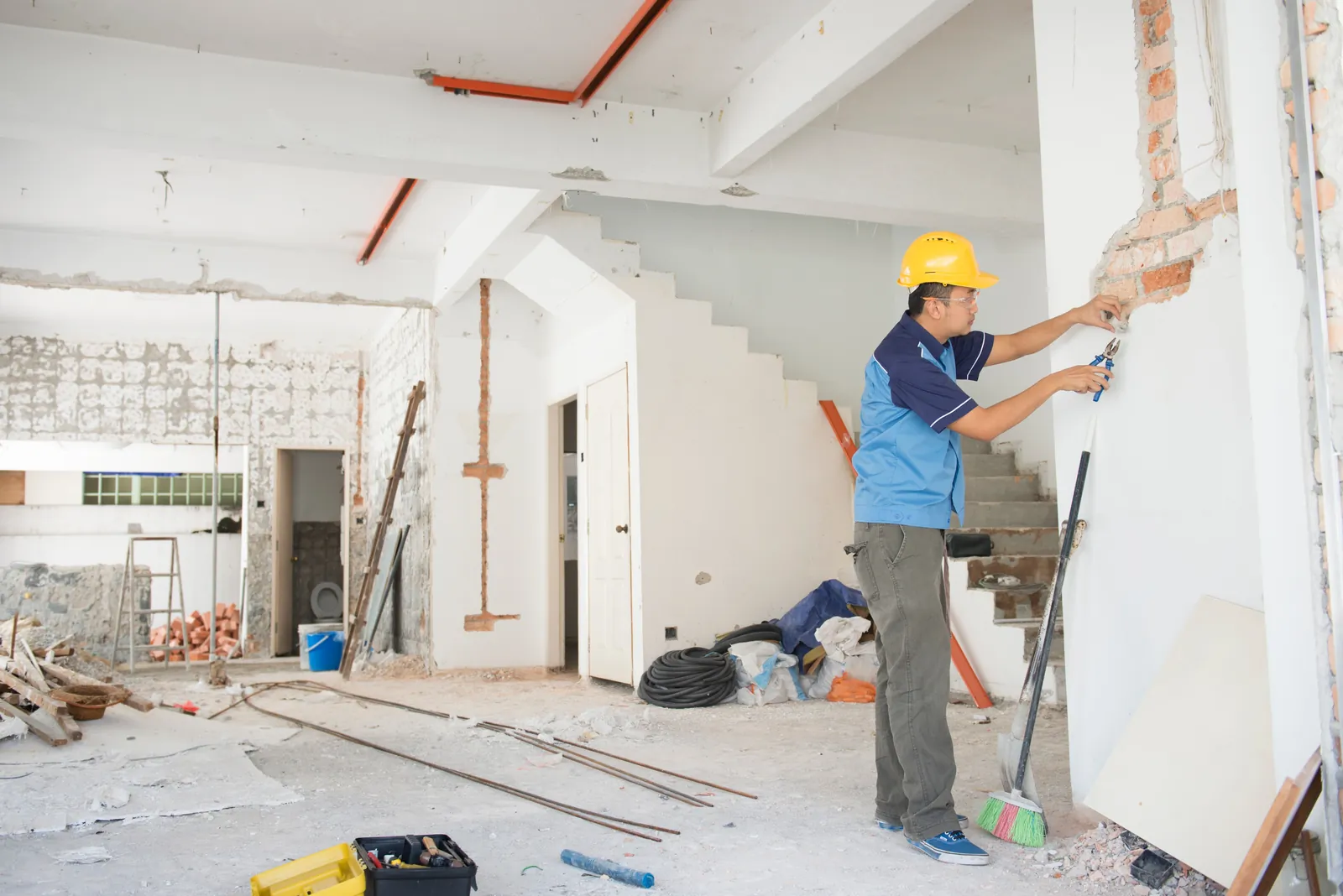 A worker in a hard hat repairing a wall in a stripped-out interior