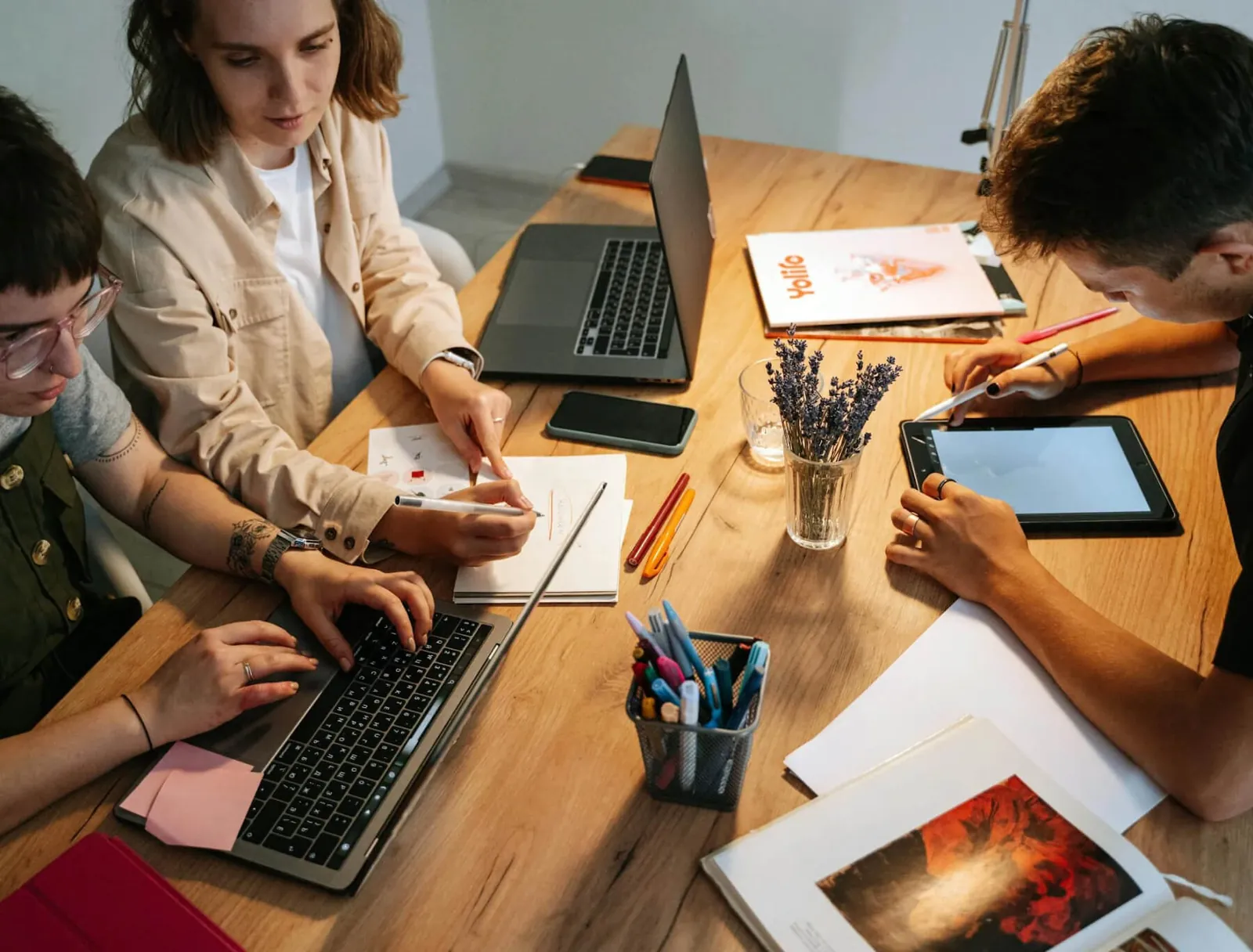 Colleagues working on laptops and tablets at a shared table