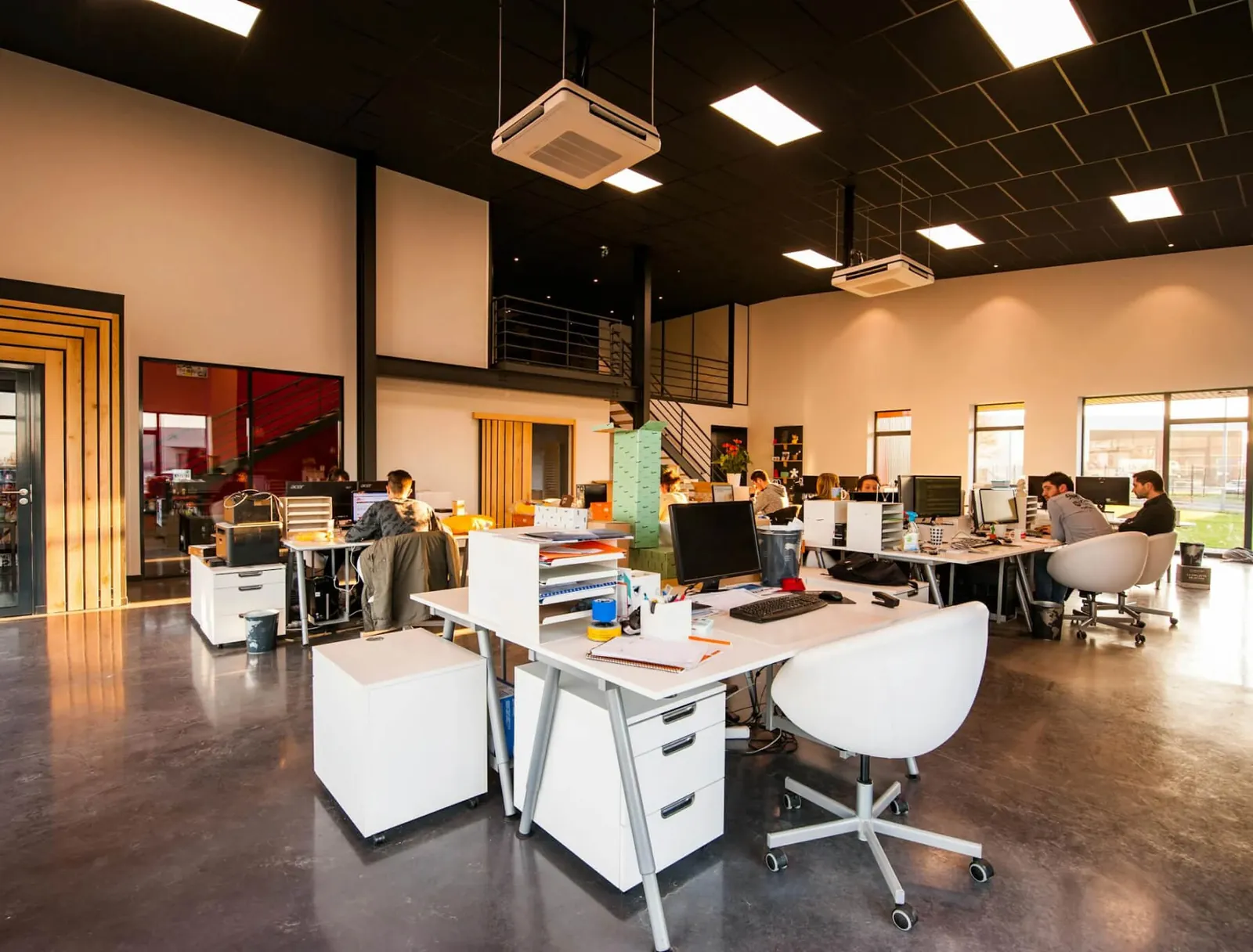 An open-plan office with desks and white chairs