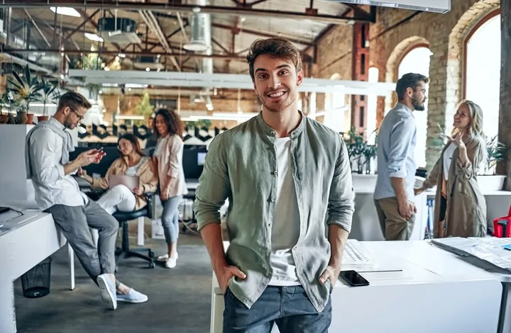 A man smiling in an open-plan office