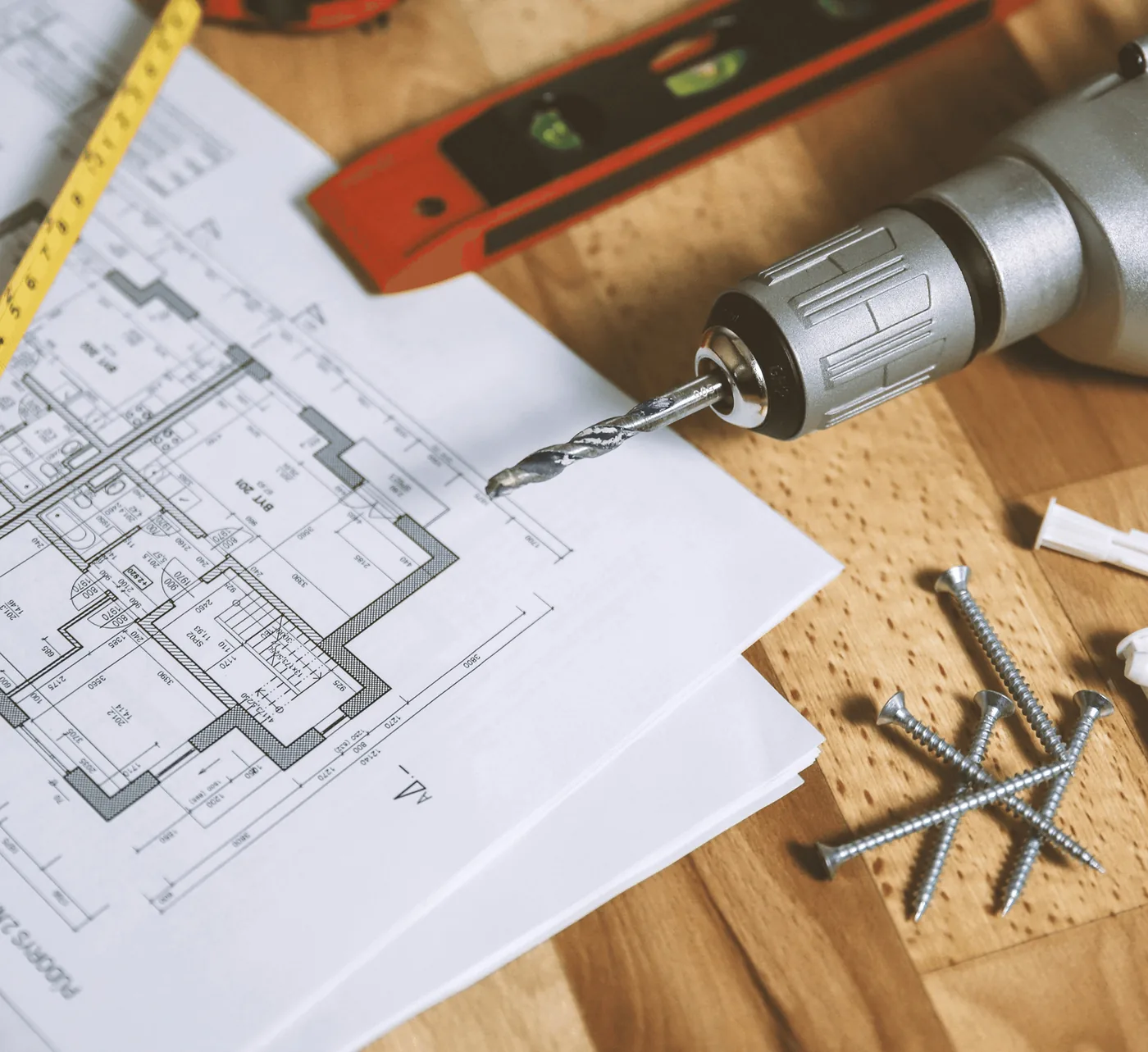 A drill, a spirit level and screws on house plans