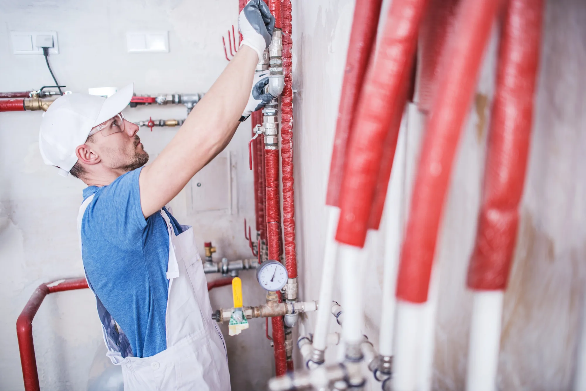 A plumber in a blue cap at a utility room