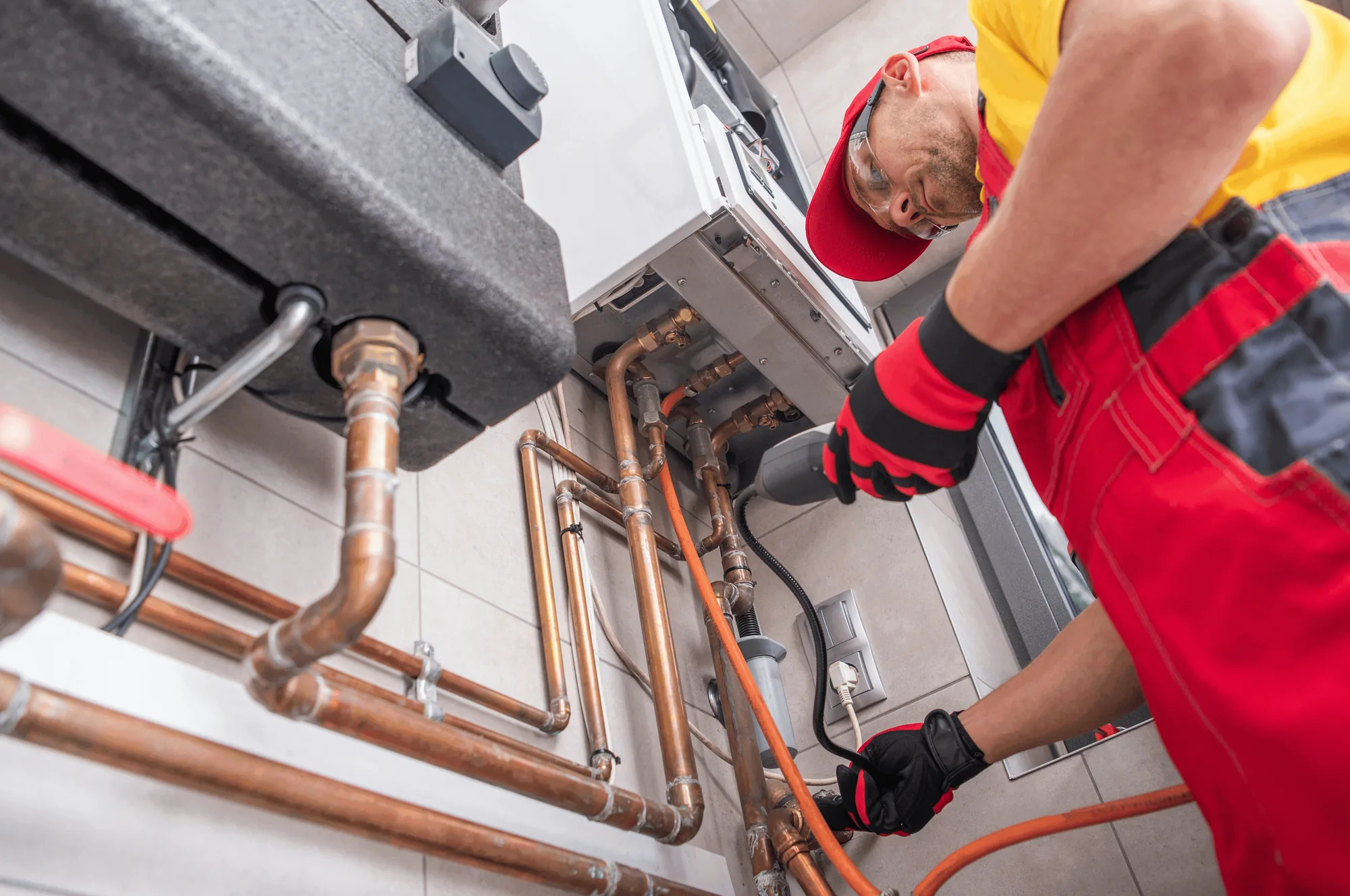 A plumber in red overalls fitting copper pipework