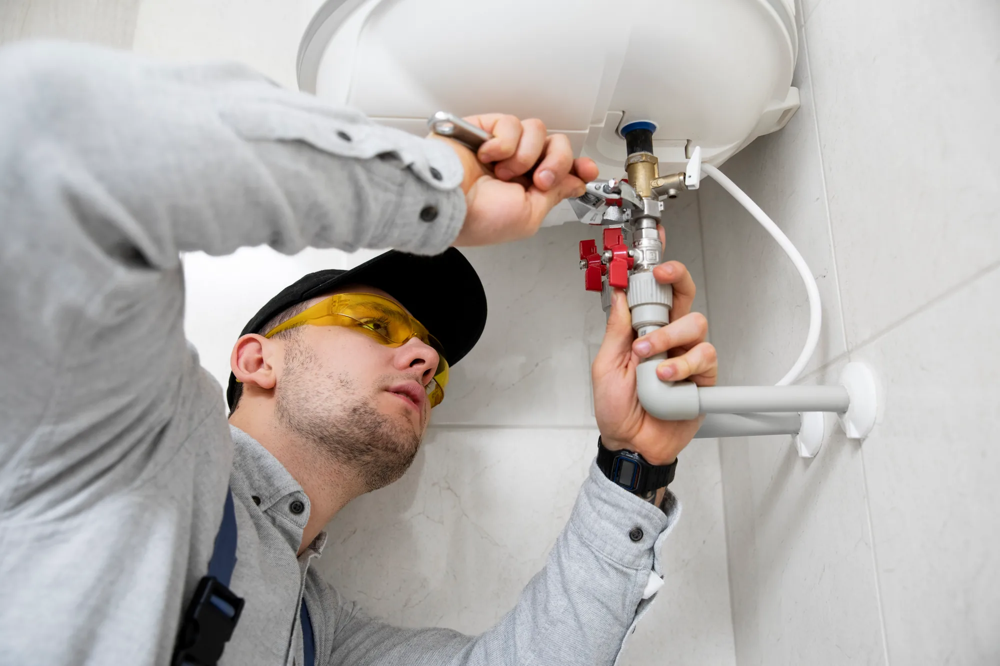 A plumber repairing pipes in a cabinet