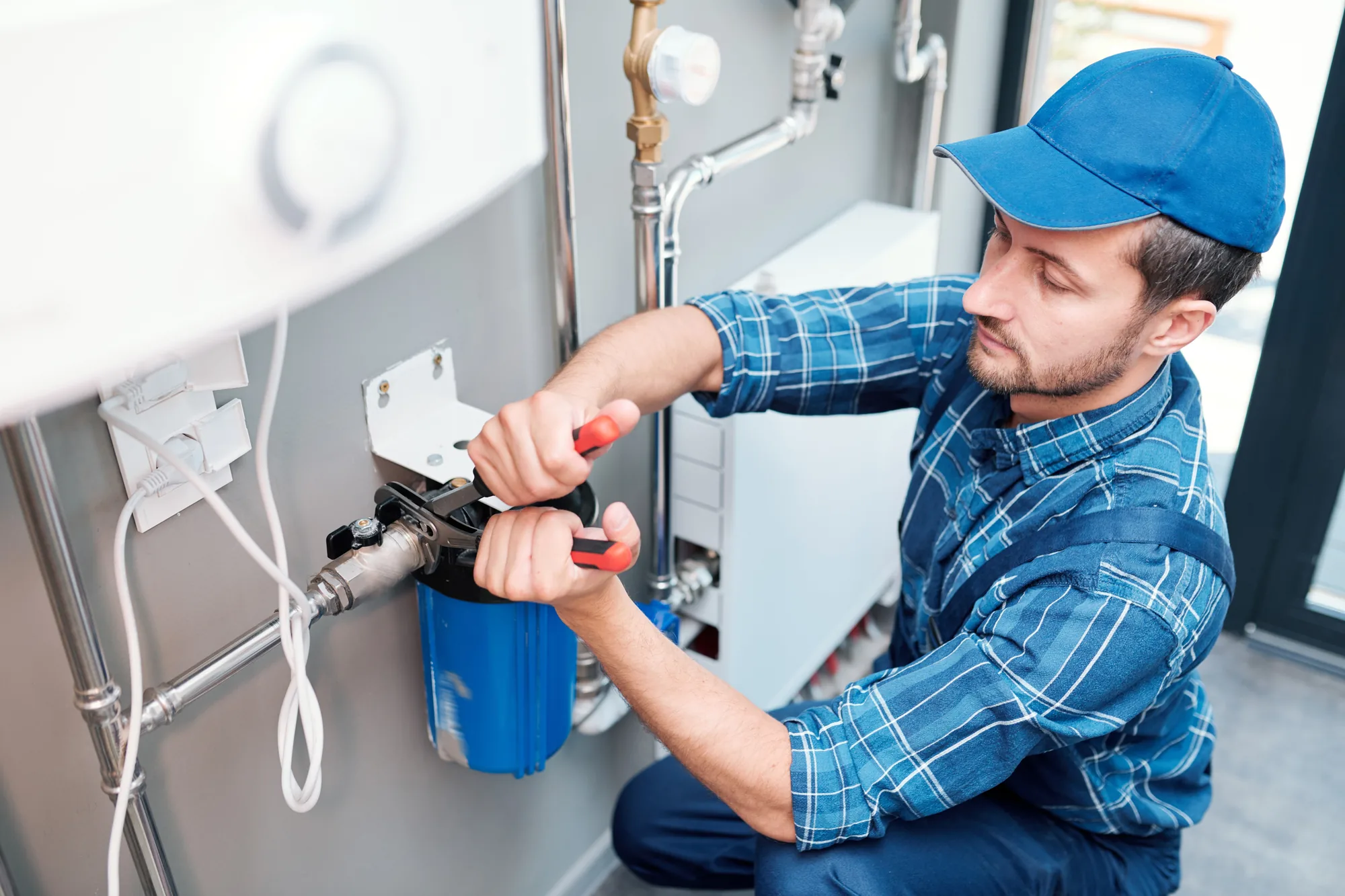 A plumber adjusting a wall-mounted boiler