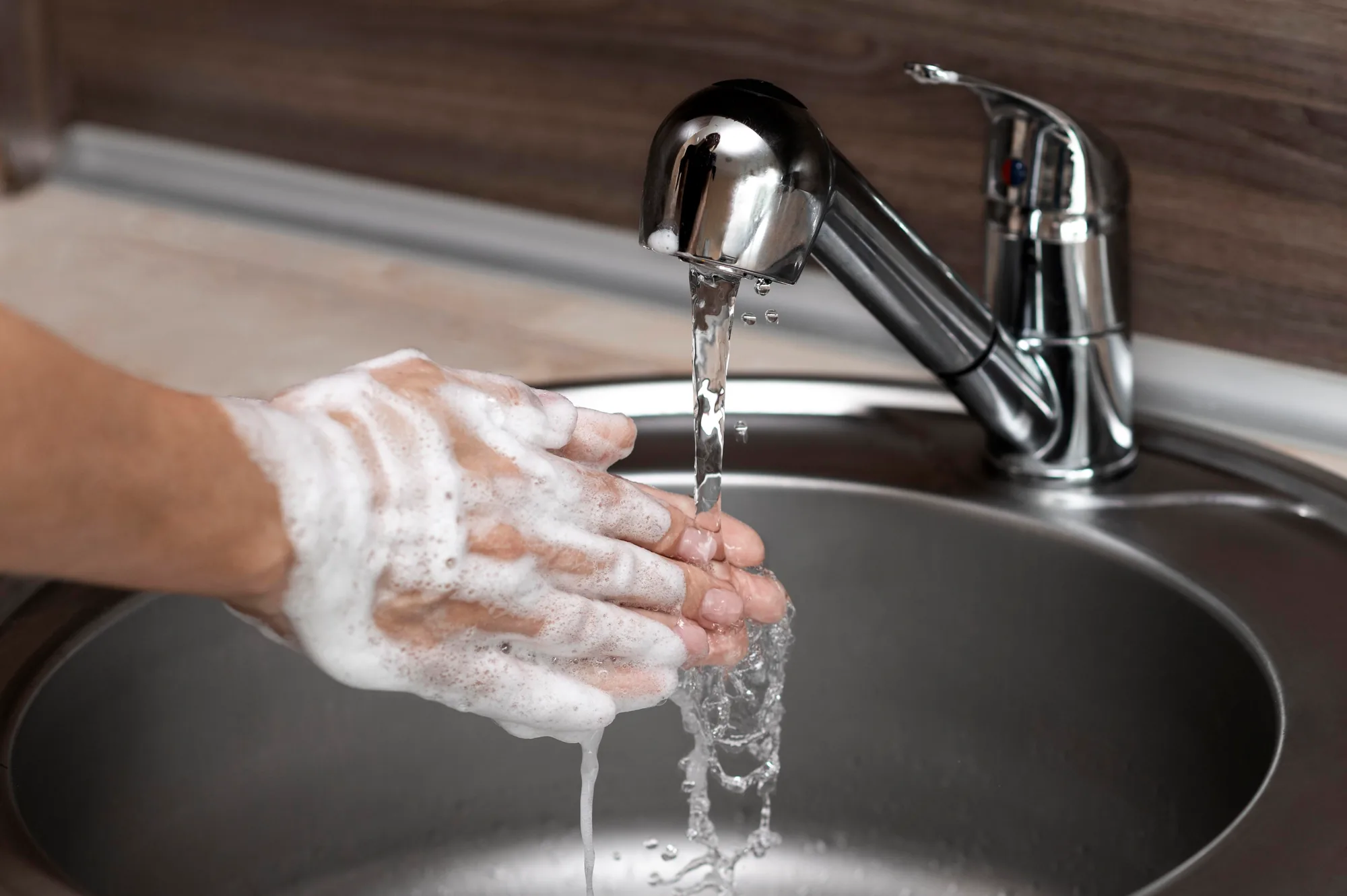 Hands rinsed with soap under a tap