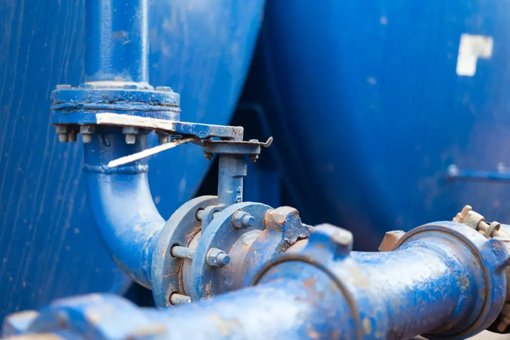 Blue pipework and a valve beside two water tanks