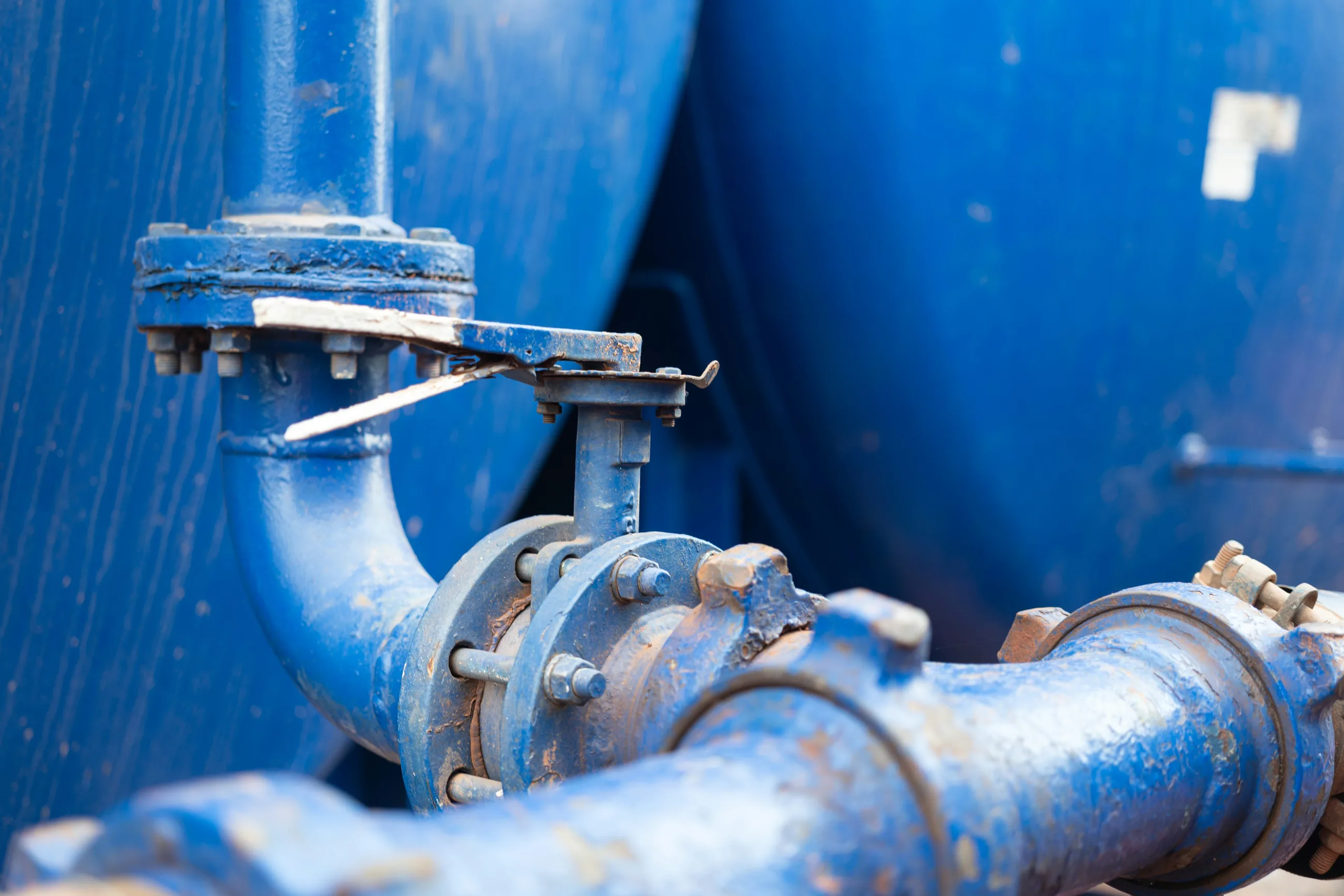 Blue pipework and a valve beside two water tanks