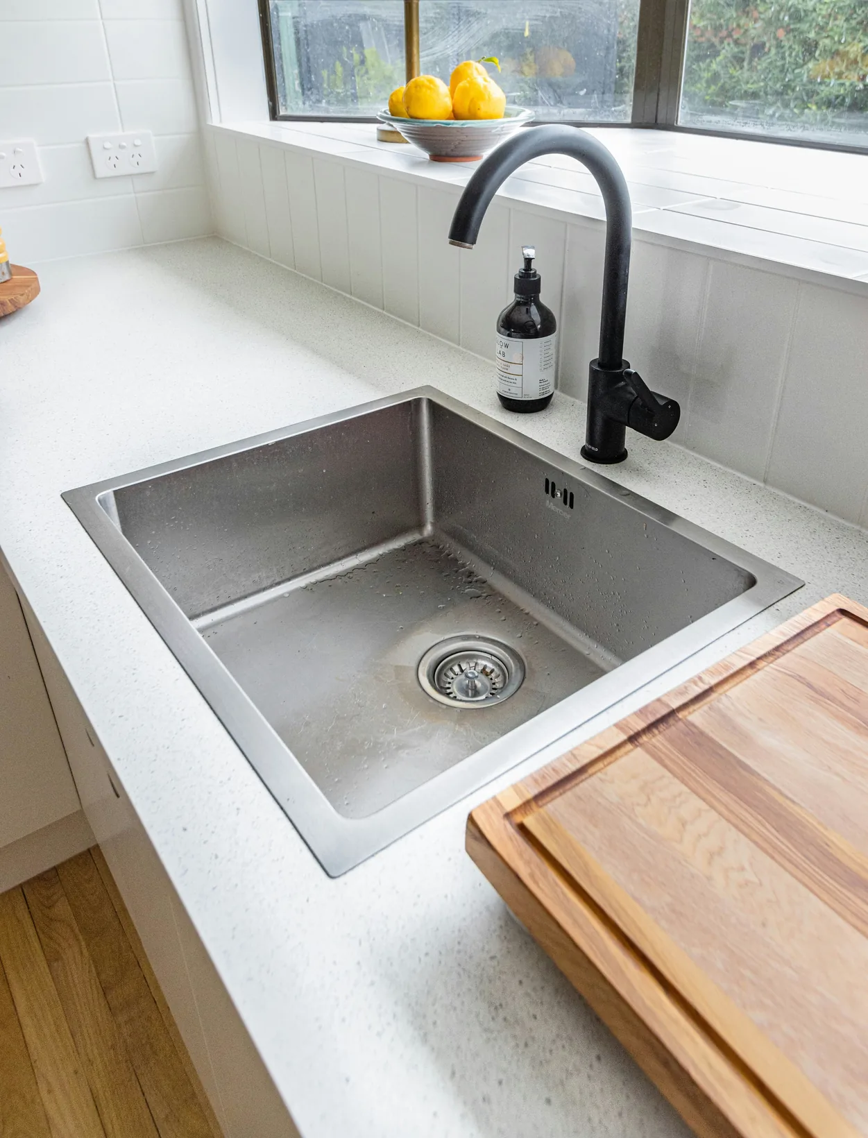 A black tap over a clean steel kitchen sink