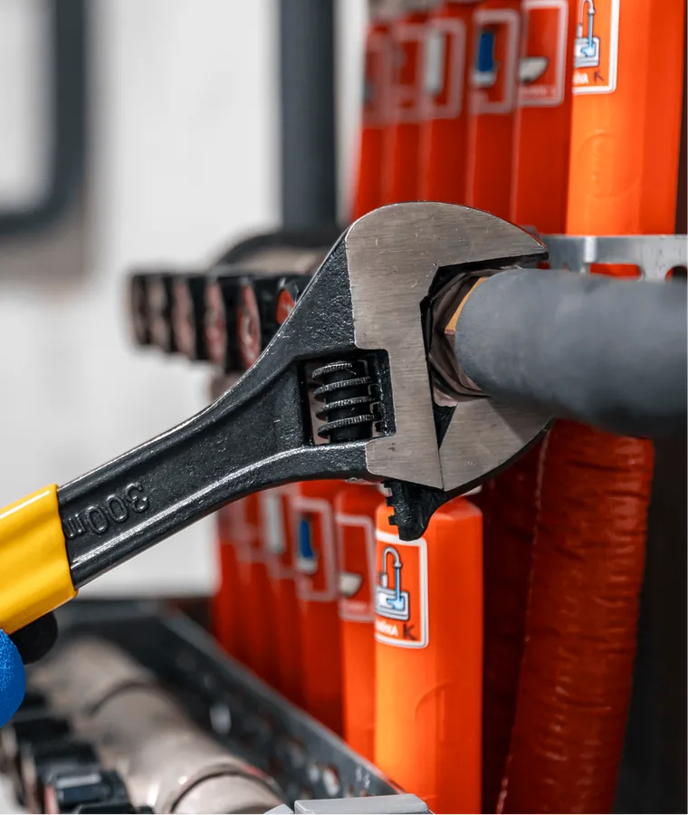 A wrench gripping a pipe beside orange fittings