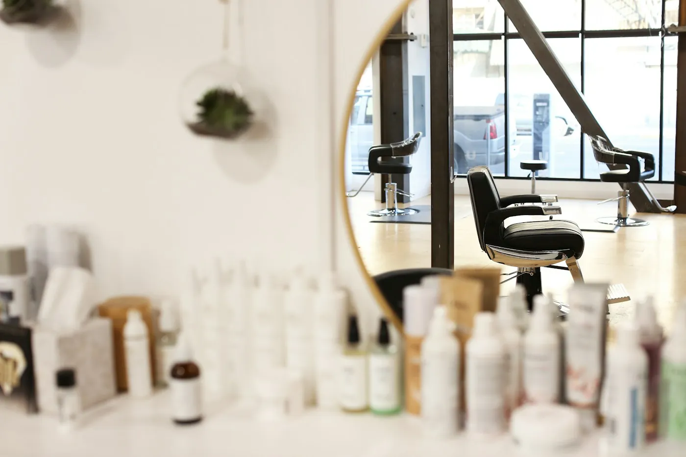 A bright salon with a round mirror, a styling chair and shelves of hair products