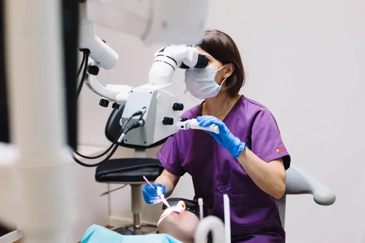 A dentist treating a patient under a microscope